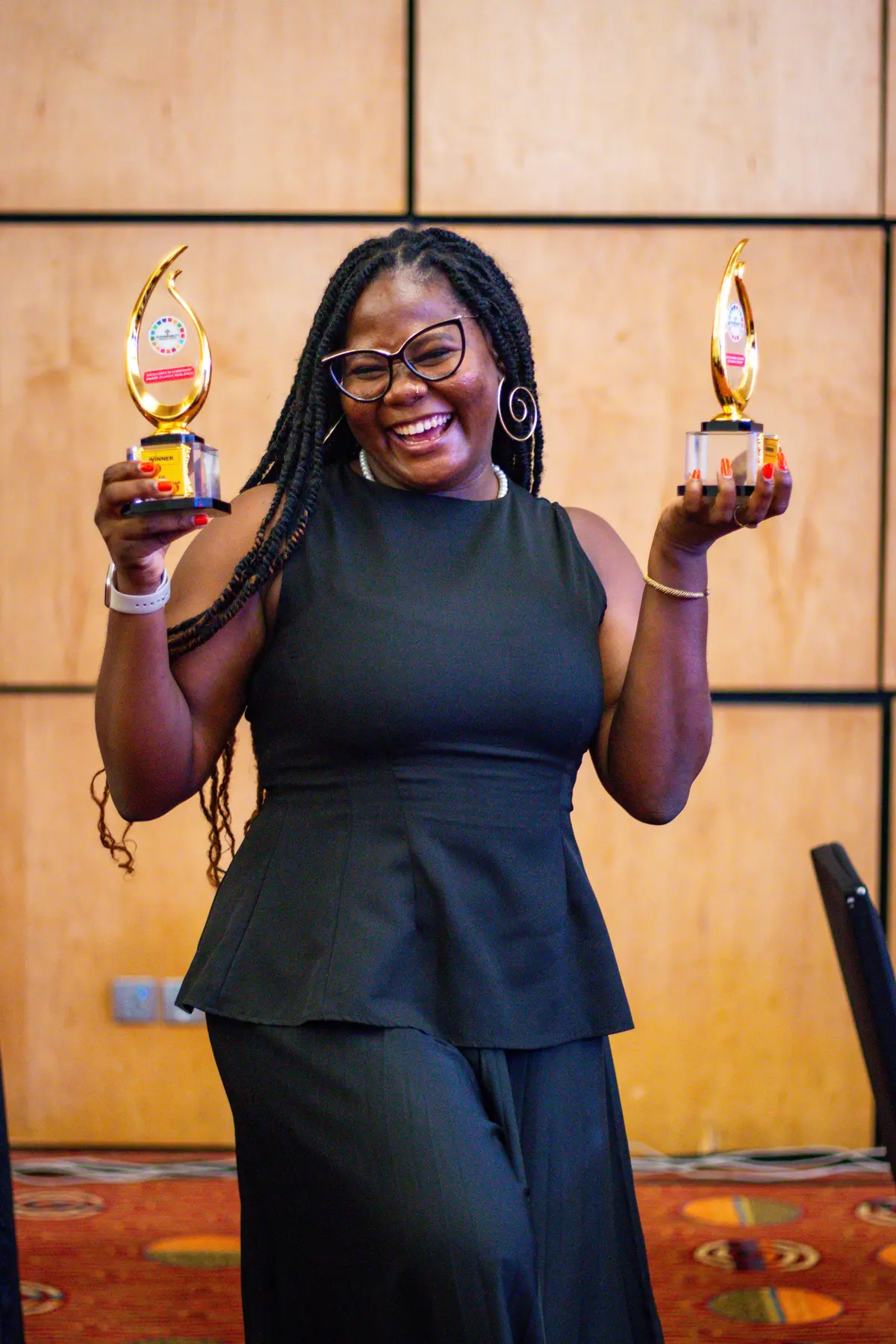 A woman holding two ESG and Sustainability Awards on stage